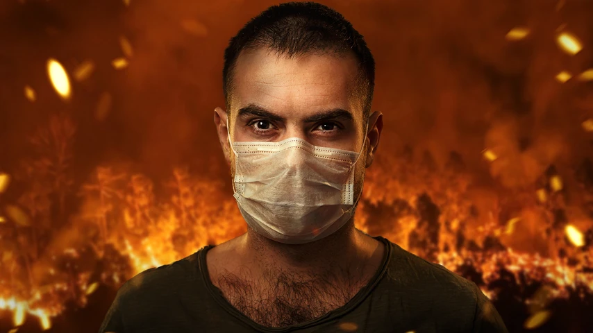 A man in a medical mask to protect the cuts of breath against the backdrop of severe forest fires. The concept of fires in Australia.